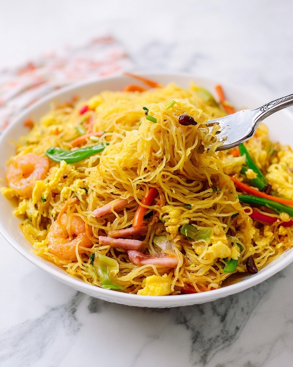 The image shows a white bowl full of thin yellow noodles mixed with small pieces of scrambled egg, thin carrot strips, green beans, slices of onion, red bell pepper, and thin strips of ham. The noodles are piled in layers with the vegetables and ham scattered throughout, adding color and texture. A silver fork is lifting a bite of noodles from the bowl. The bowl is placed on a white marbled surface. photo taken with an iphone --ar 4:5 --v 7