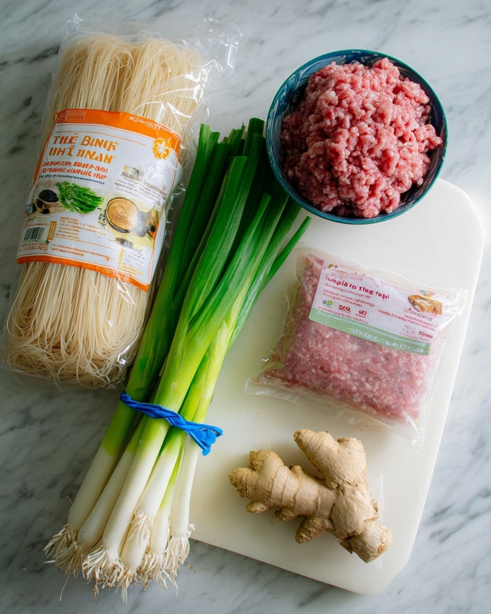 The image shows five cooking ingredients placed on a white marbled surface. On the left, there is a bunch of fresh green onions tied together with a rubber band, showing long green stalks with white bottoms. Next to it, a clear package of rice noodles stands upright with an orange bottom half and white top half, the noodles visible inside and the words 