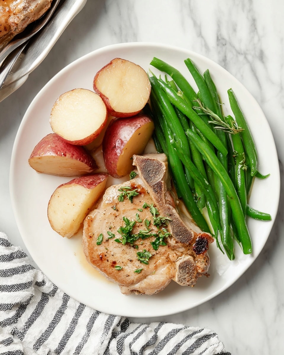 On a white plate, there is one large piece of cooked pork chop with a light brown color and some charred spots, placed at the bottom right. To the left of the pork chop, there are several red potato pieces with a pale inside, stacked unevenly. Above the pork chop and potatoes, a small group of green beans lies neatly, adding a bright green color to the plate. The plate rests on a white marbled surface with a black and white striped cloth nearby. photo taken with an iphone --ar 4:5 --v 7