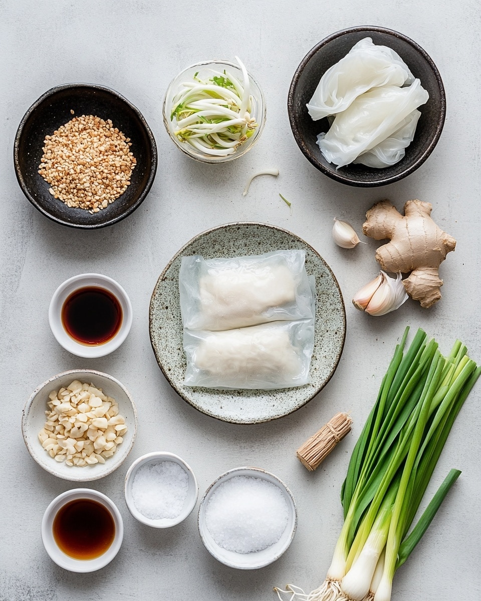 A row of four pan-fried dumplings is placed side by side on a white plate resting on a white marbled surface. Each dumpling has a golden brown, crispy top layer with small green herbs visible inside, surrounded by a slightly translucent, soft dough layer that forms the base and sides. A pair of wooden chopsticks held by a woman's hand is grasping the first dumpling in the row. There are small green onion pieces scattered around the plate and a white bowl with red dipping sauce blurred in the background. The lighting highlights the texture and color contrast between the dumpling's crispy top and the soft dough. photo taken with an iphone --ar 4:5 --v 7